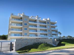 un edificio de apartamentos alto y blanco con una pared en Emerald Apartments - Parrillero exclusivo, en Punta del Este