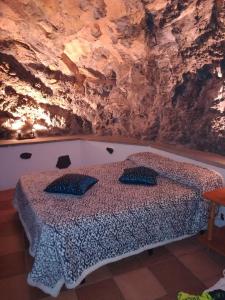 a bedroom with a bed in front of a rock wall at Casa cueva El perucho in Güimar