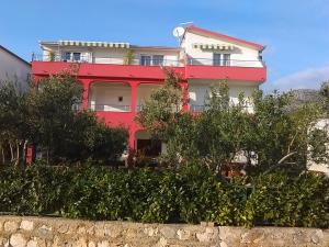a red and white building with trees in front of it at Apartments Mare - 30m from beach in Seget Vranjica