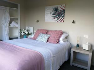 Mont's Cottage في Awatuna: غرفة نوم مع سرير وملاءات ووسائد وردية