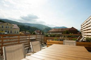 a wooden table and chairs on a balcony with mountains at Family fun Pohorje in Ruše