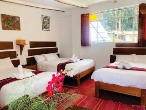 a room with three beds with flowers in it at Inka Khawarina Tambo Lodge in Ollantaytambo