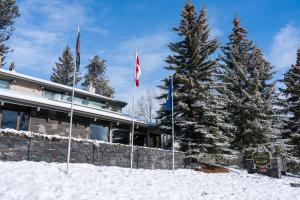 three flags in the snow in front of a building at Tunnel Mountain Resort in Banff