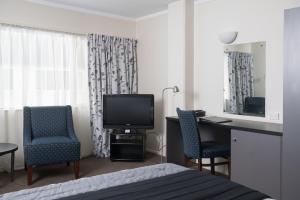a hotel room with a bed and a desk and a television at West Plaza Hotel in Wellington