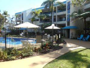 a fence with umbrellas in front of a building at Placid Waters Holiday Apartments in Bongaree