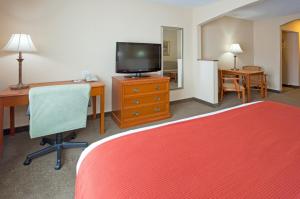 ein Hotelzimmer mit einem Bett, einem Schreibtisch und einem TV in der Unterkunft Days Inn & Suites by Wyndham La Crosse-Onalaska in Onalaska