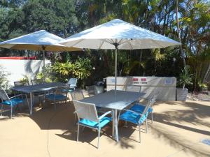 2 tafels en stoelen met parasols op een patio bij Placid Waters Holiday Apartments in Bongaree