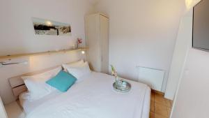 ペルツァーハケンにあるFeriendorf Südstrand Haus 7の小さなベッドルーム(白いベッド、青い枕付)