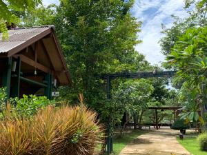 un jardin avec une pergola en bois et des arbres dans l'établissement Nung Ni Bang Khon Thi Resort, à Amphawa