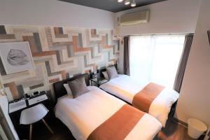 a hotel room with two beds and a window at Forest Inn Fukuoka -previously Pure Tenjin- in Fukuoka