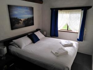 a bedroom with a white bed with blue curtains and a window at Sandy Bay Holiday Park in Busselton