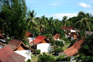 eine Gruppe von Häusern mit roten Dächern und Palmen in der Unterkunft Frangipani Langkawi Resort in Pantai Cenang