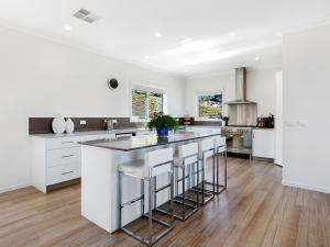 a white kitchen with a large island with bar stools at George River Park (House, 100 Acres, Animals, Views) in St Helens