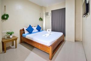 a bedroom with a bed with blue and white pillows at Boracay Backpackers in Boracay