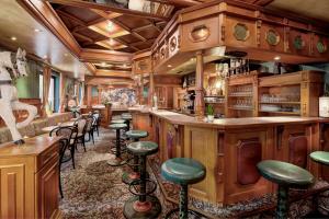 a bar with wooden cabinets and green stools at Martini's B&B Kaprun including summercard in Kaprun