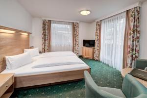 a hotel room with a large bed and chairs at Hotel Martini Kaprun - including summercard in Kaprun
