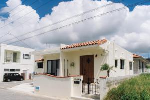 une maison blanche avec un portail et une clôture dans l'établissement Villa Mahalo ＜1日１組限定＞, à Yomitan