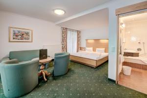 カプルーンにあるHotel Martini Kaprun - including summercardのベッド、デスク、椅子が備わるホテルルームです。