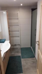baño con lavabo y ducha con alfombras verdes en Ferienwohnung Haiberg en Rudolfing