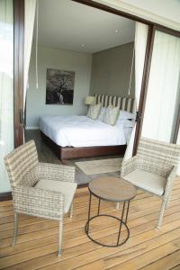 1 Schlafzimmer mit einem Bett, 2 Stühlen und einem Tisch in der Unterkunft Le Elementos Boutique Hotel in Lusaka