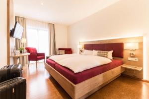 a bedroom with a large bed with a red bench at Schmidtburger Hof in Weiler