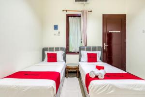 two beds sitting next to each other in a room at RedDoorz Syariah @ Ketintang Surabaya in Surabaya