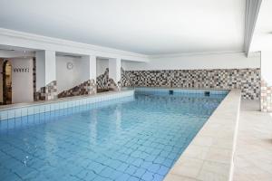 an indoor swimming pool with blue tiles on the walls at Hotel Serles in Mieders