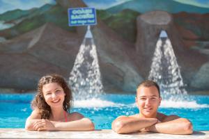 a man and a woman sitting in a swimming pool at SPA Hotel Elbrus in Velingrad