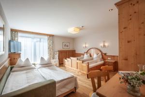 a bedroom with two beds and a living room at Hotel Garni Tirolerhof in Hopfgarten im Brixental