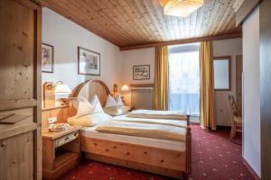 Schlafzimmer mit einem großen Bett mit einem Kopfteil aus Holz in der Unterkunft Hotel Garni Tirolerhof in Hopfgarten im Brixental