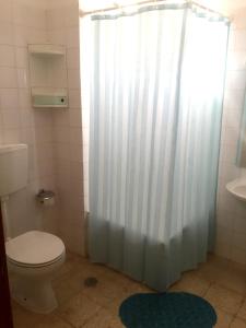 a bathroom with a toilet and a shower curtain at HI Alcoutim – Pousada de Juventude in Alcoutim