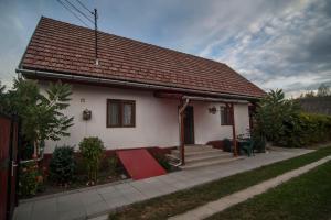 una pequeña casa blanca con una alfombra roja delante de ella en Dobra Haz, en Covasna