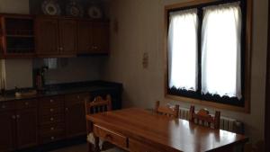 a kitchen with a wooden table and two windows at Casa de Campo in Potes