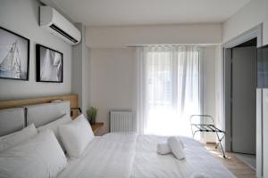 a bedroom with a white bed and a window at Urban Melodies Apartment in Athens