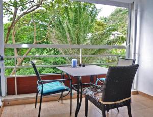 einen Tisch und Stühle auf einem Balkon mit Fenster in der Unterkunft Toupidek-sur-la-Plage in Arue