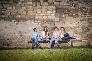 four girls sitting on a bench against a brick wall at Schmidtburger Hof in Weiler