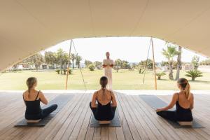 a group of three women sitting in a yoga class at Gecko Hotel & Beach Club, a Small Luxury Hotel of the World in Playa Migjorn