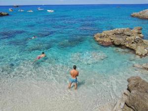 2 personnes nageant dans l'eau sur une plage dans l'établissement Residence Praia di Fuoco, à Capo Vaticano