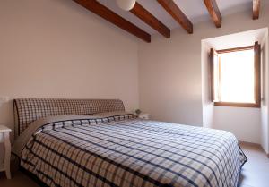 a bedroom with a bed with a checkered blanket and a window at Can Calet in Marratxí 