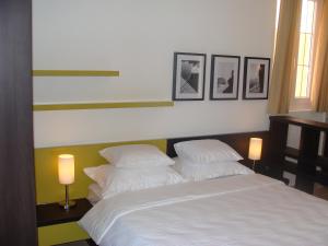 a bedroom with a bed with two lamps and pictures on the wall at Apartments Danilo Kažanegra in Sveti Stefan