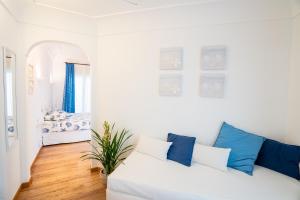 a white living room with a white couch and blue pillows at Covo dei Saraceni in Polignano a Mare