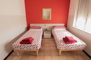 2 posti letto in una piccola camera con pareti rosse di Albergo La Rovere a Roverbella