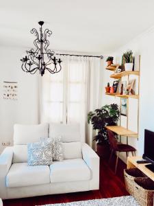 a white couch in a living room with a chandelier at Apartamento en el autentico corazón de Mundaka in Mundaka