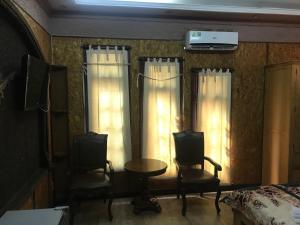 1 dormitorio con 2 sillas, mesa y cortinas en Nhật Vân 1 en Ho Chi Minh