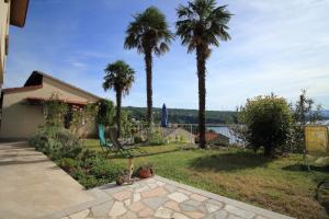 a yard with palm trees and a bench and water at Tramontana Leeward - Cozy and charming apartment in beautiful Volosko in Opatija