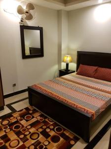 a bedroom with a bed with a mirror and a rug at Rove Lodging-One Bed Apartment,Bahria Town in Rawalpindi