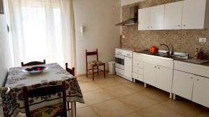 eine Küche mit weißen Schränken, einem Tisch und einem Waschbecken in der Unterkunft Appartamenti Torre Lapillo in Torre Lapillo