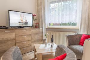 a living room with a tv and a table at Hotel Garni Kröger in Wittmund