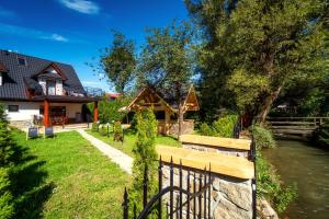 a house with a fence next to a river at Domek u Eli in Czarny Dunajec