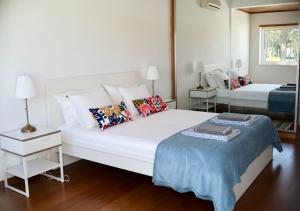 ein weißes Schlafzimmer mit einem großen weißen Bett mit Kissen in der Unterkunft Faulha House,with BBQ and swimming pool in Sesimbra